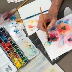 An artist skillfully painting vibrant flowers using watercolor on paper, showcasing creative artistry.