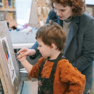 A mother helps her child paint in an art studio, fostering creativity and learning.